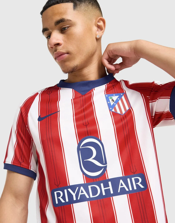 Dettaglio stemma retro Atletico Madrid e colletto a V blu navy sulla maglia Home 2026/2027