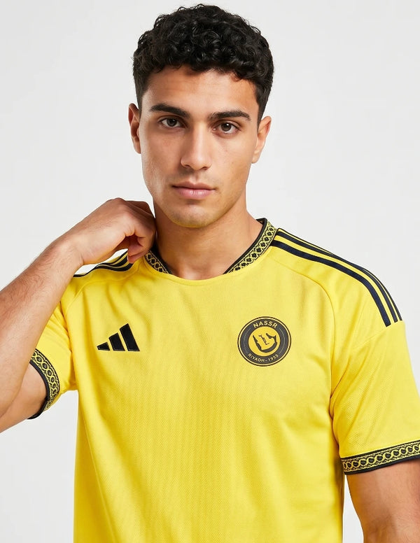 Dettaglio stemma Al Nassr Riyadh 1955 sulla Maglia Home 2026/2027 Adidas con pattern arabesco sul colletto