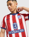 Dettaglio stemma retro Atletico Madrid e colletto a V blu navy sulla maglia Home 2026/2027
