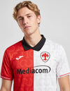 Dettaglio maglia Fiorentina Centenario 2026/2027 Joma stemma giglio e collo nero