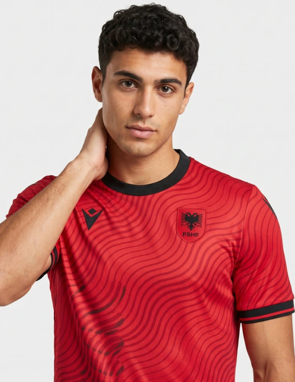 Dettaglio maglia Albania Home 2026 Macron con stemma FSHF aquila nera a due teste e colletto girocollo nero su fondo rosso