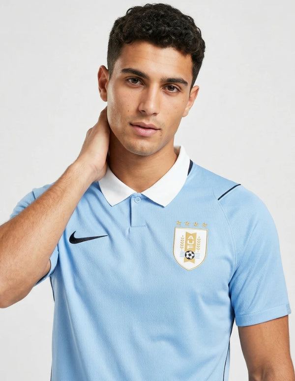 Dettaglio maglia Uruguay Home 2026 Nike con stemma AUF quattro stelle dorate e colletto polo bianco